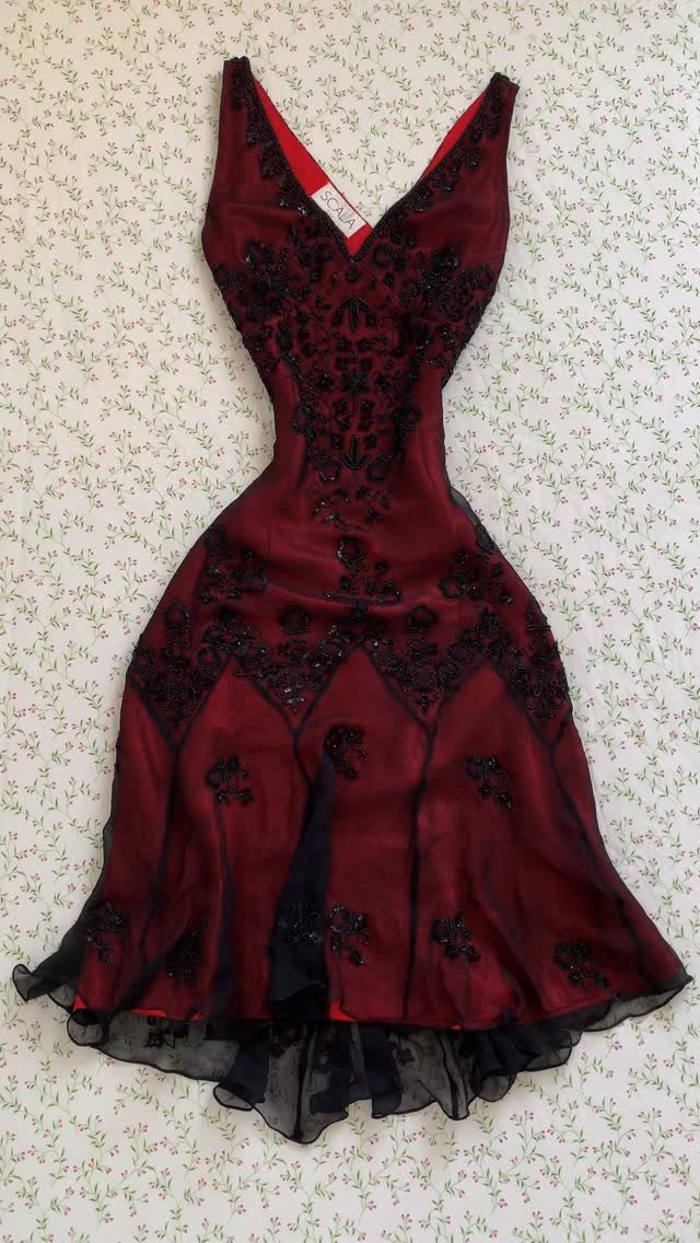 Dark red dress with black beaded embroidery and lace detailing laid on a floral surface.