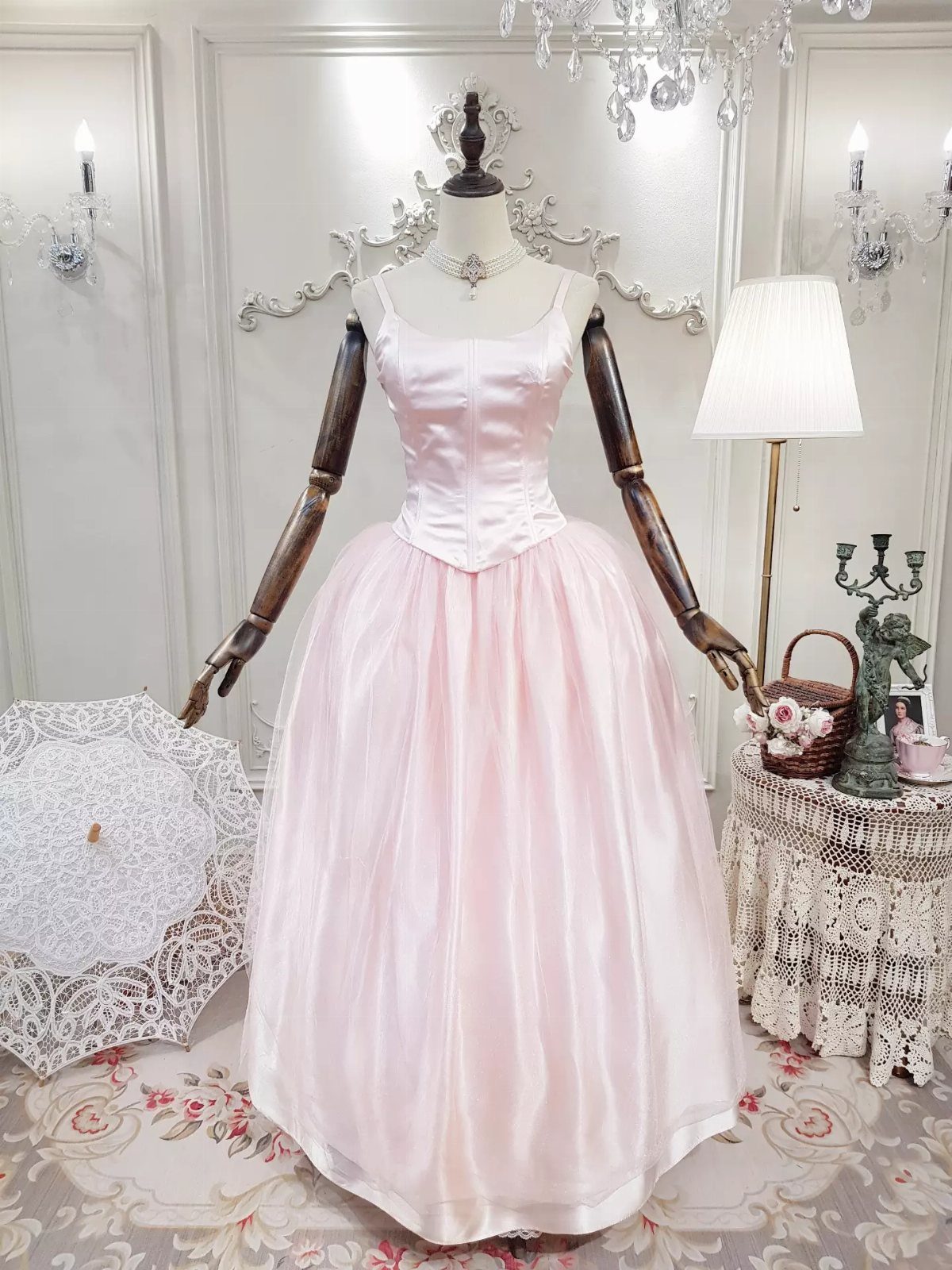A light pink satin prom dress with a fitted bodice displayed on a mannequin.