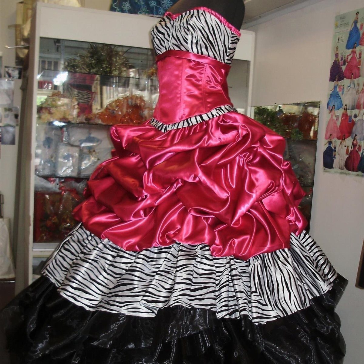 A pink and zebra print ruffled prom dress displayed on a black mannequin.
