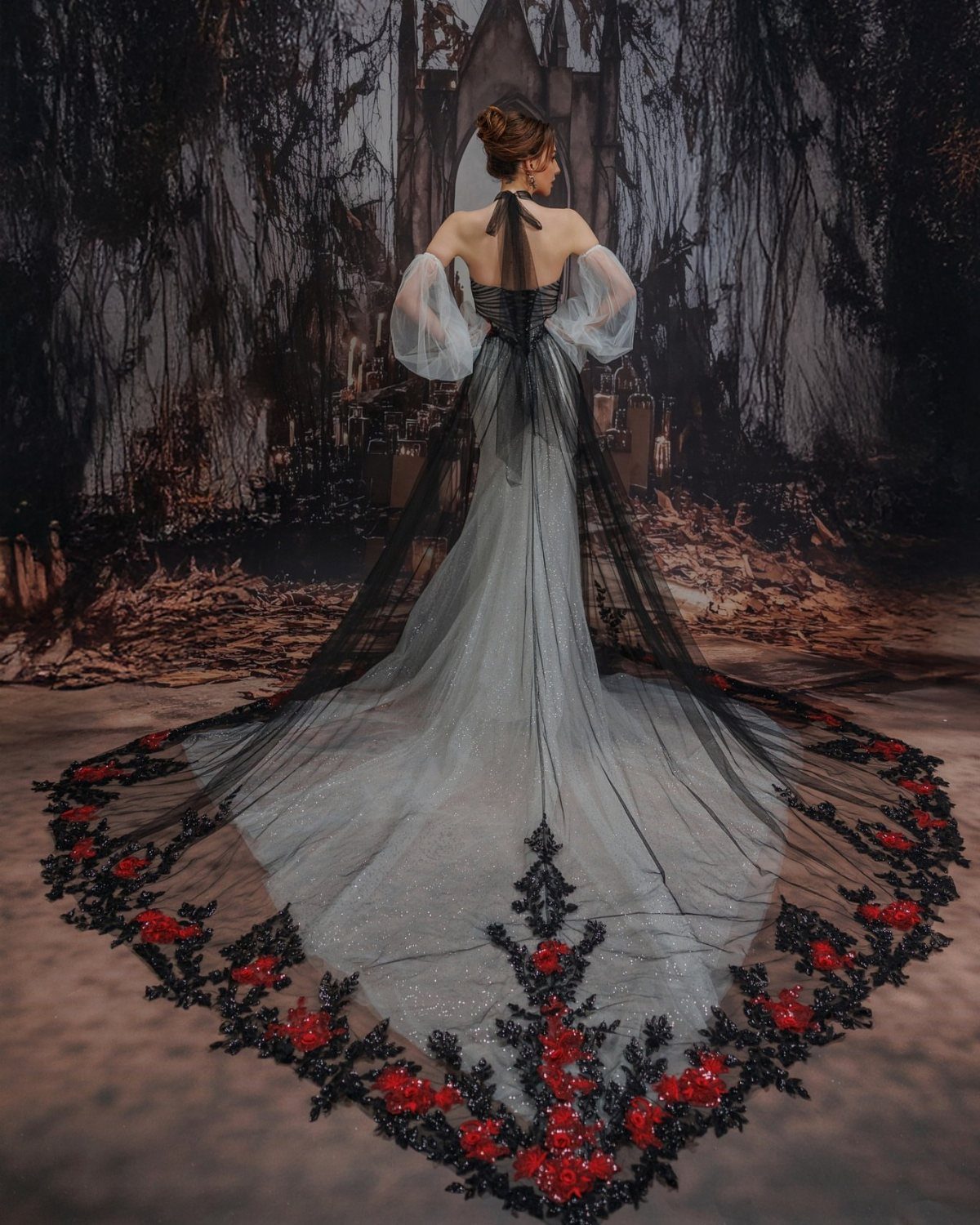 Woman in a white gown with a long black and red embroidered train.