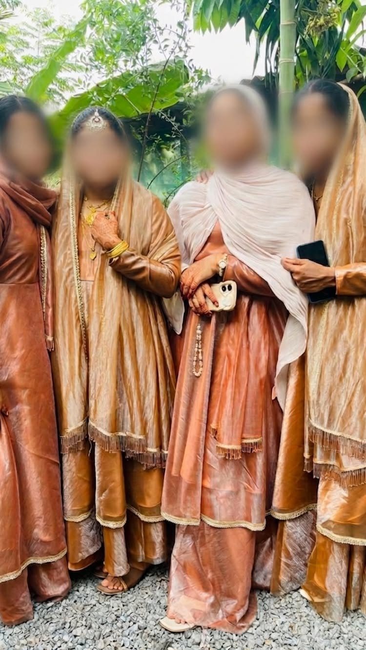 Four women in traditional copper and gold South Asian formal outfits standing together outdoors.