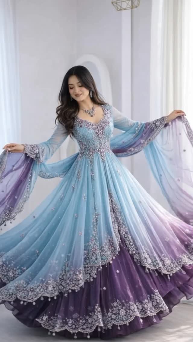 Woman wearing a flowing blue and purple embroidered gown with wide sheer sleeves.