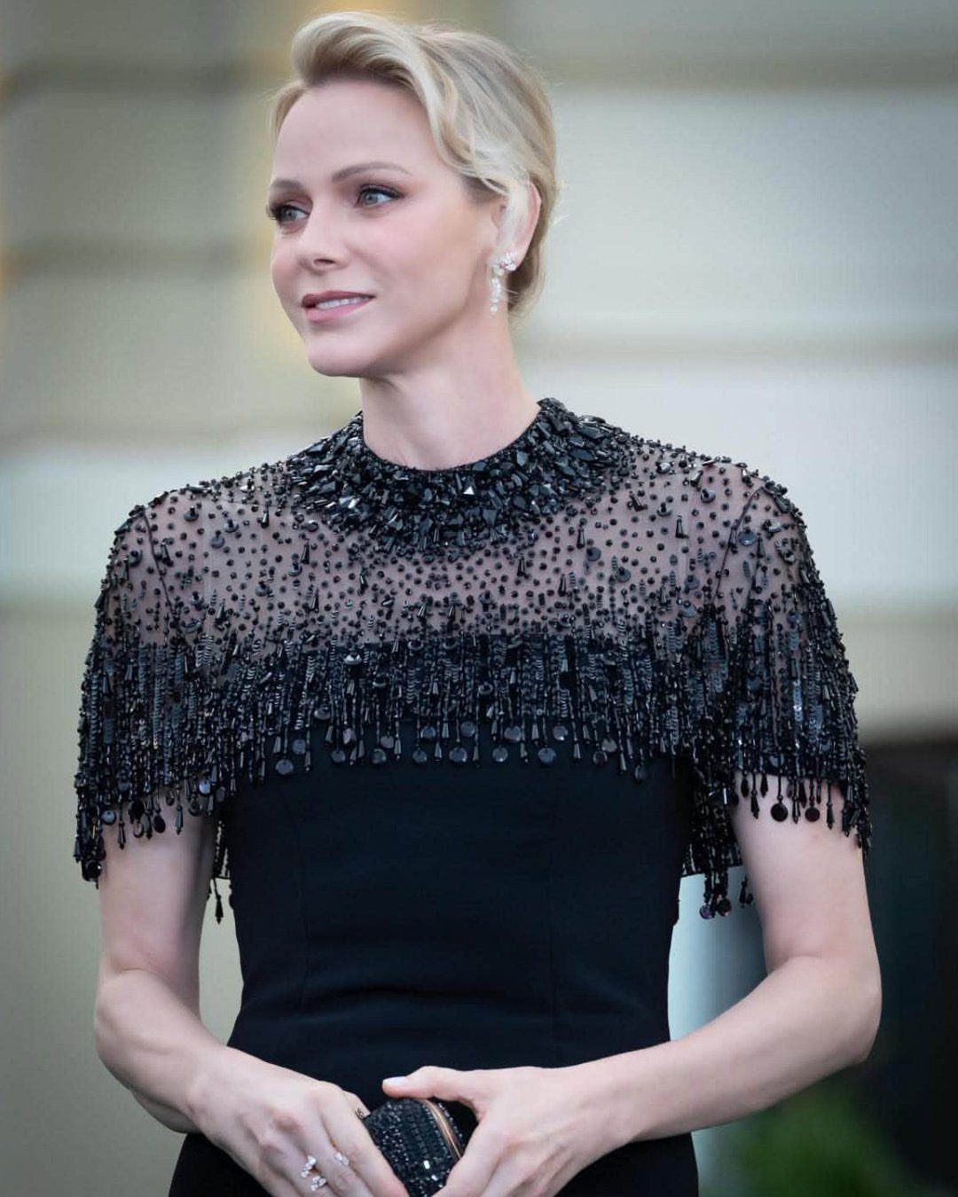 Blonde woman in a black beaded dress and sparkling drop earrings.