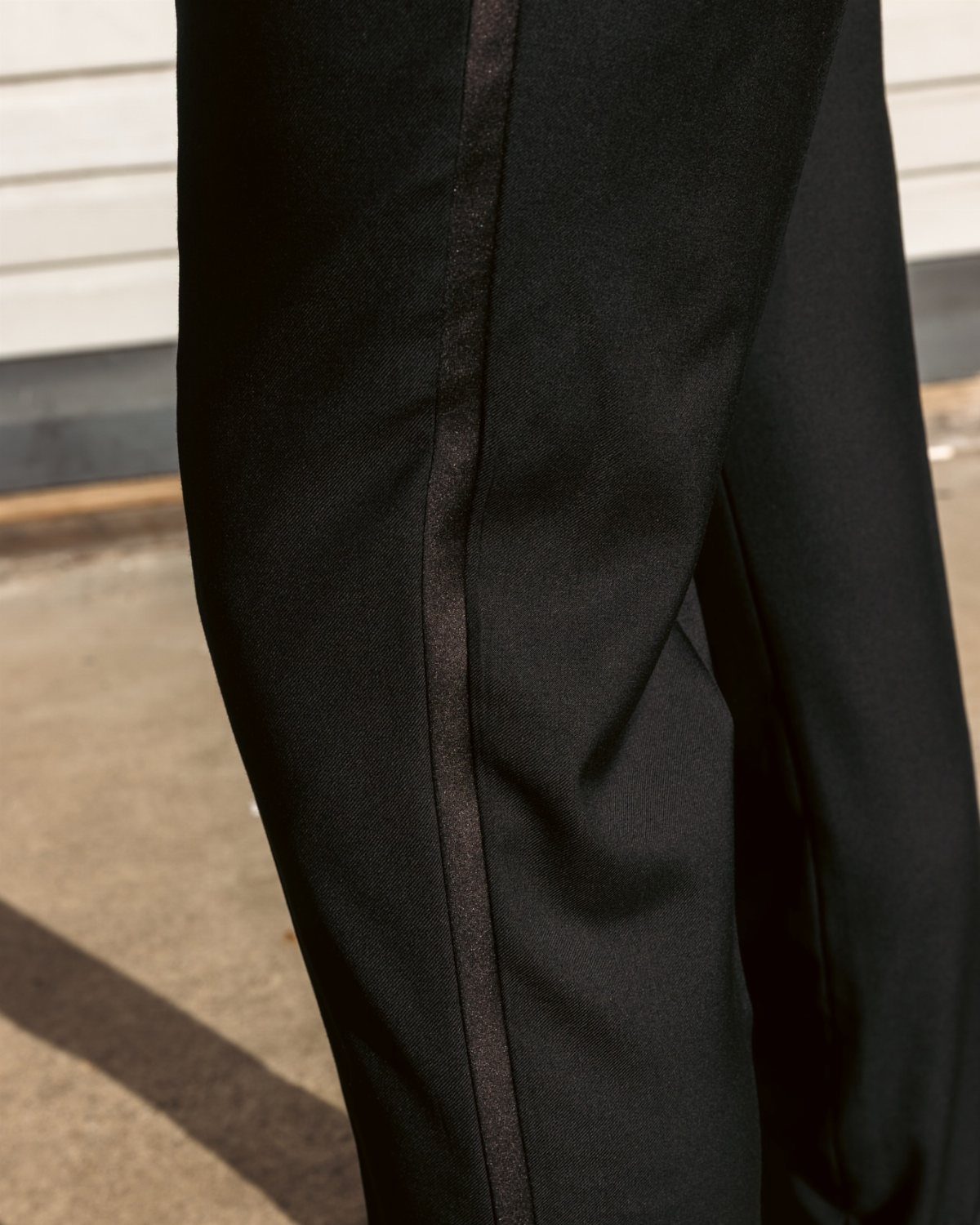 Black formal trousers with a vertical satin stripe running down the side of the leg.