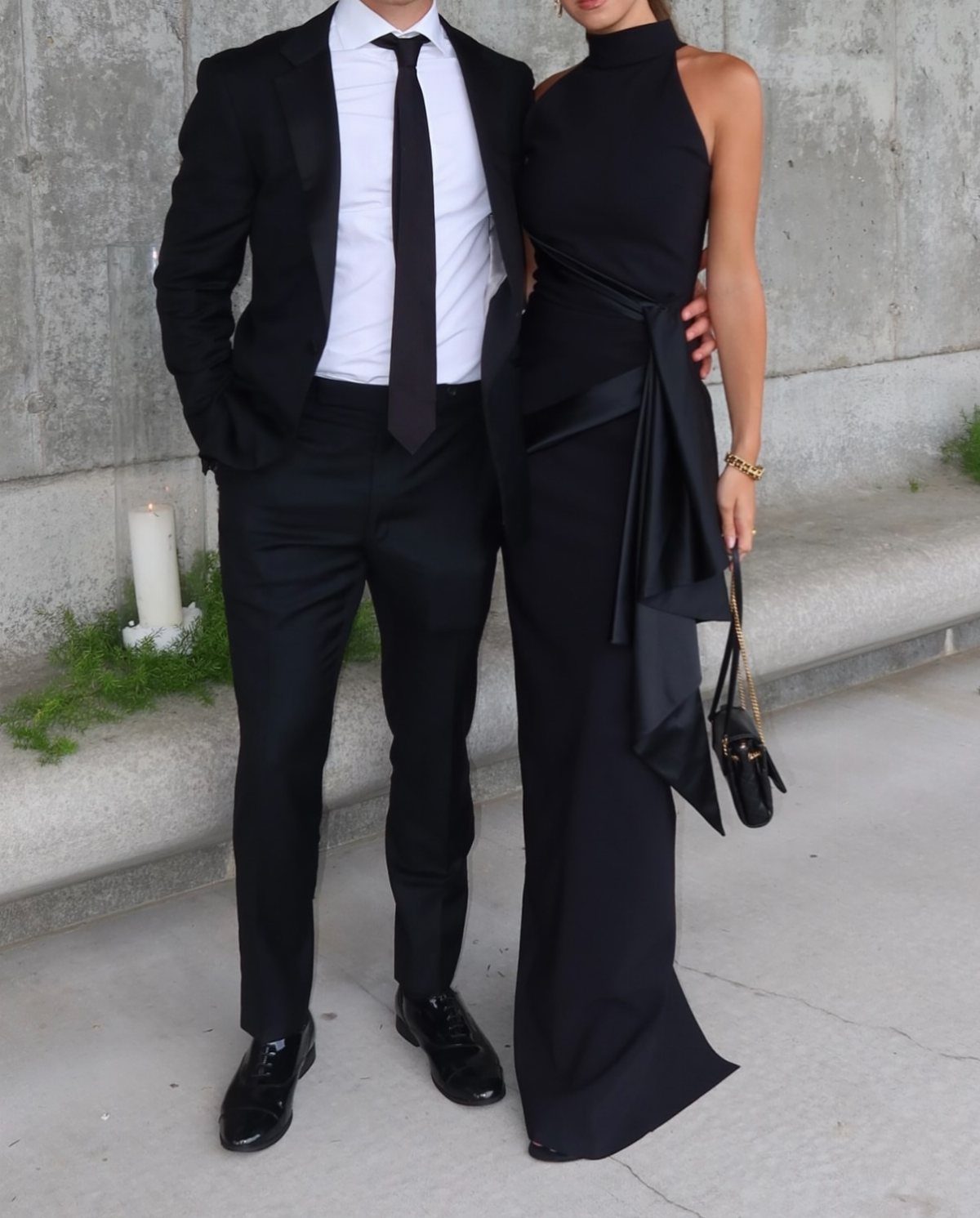 A man in a black suit and a woman in a long black halter gown standing together.