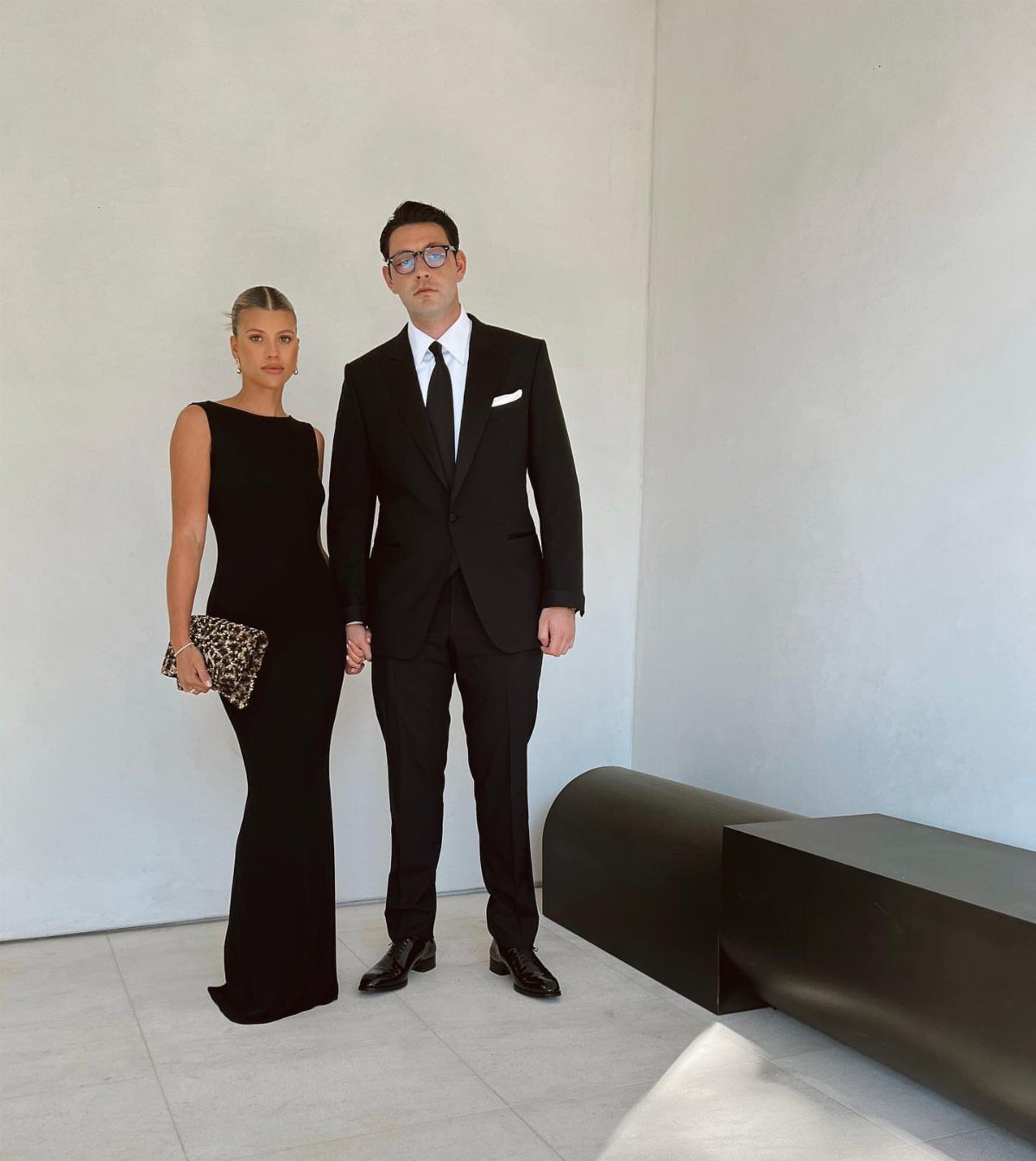 A woman in a black gown and a man in a black suit posing together.