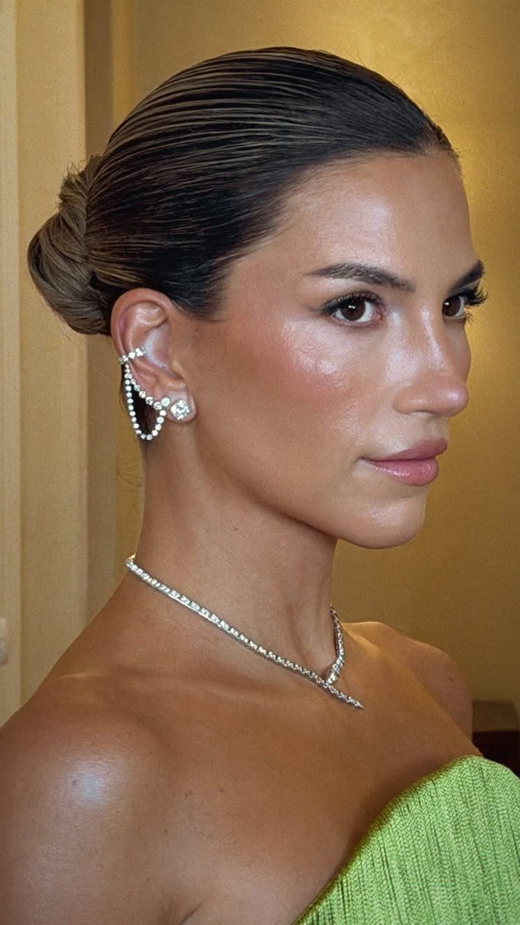 A woman wearing a sparkling diamond ear cuff and a matching tennis necklace.
