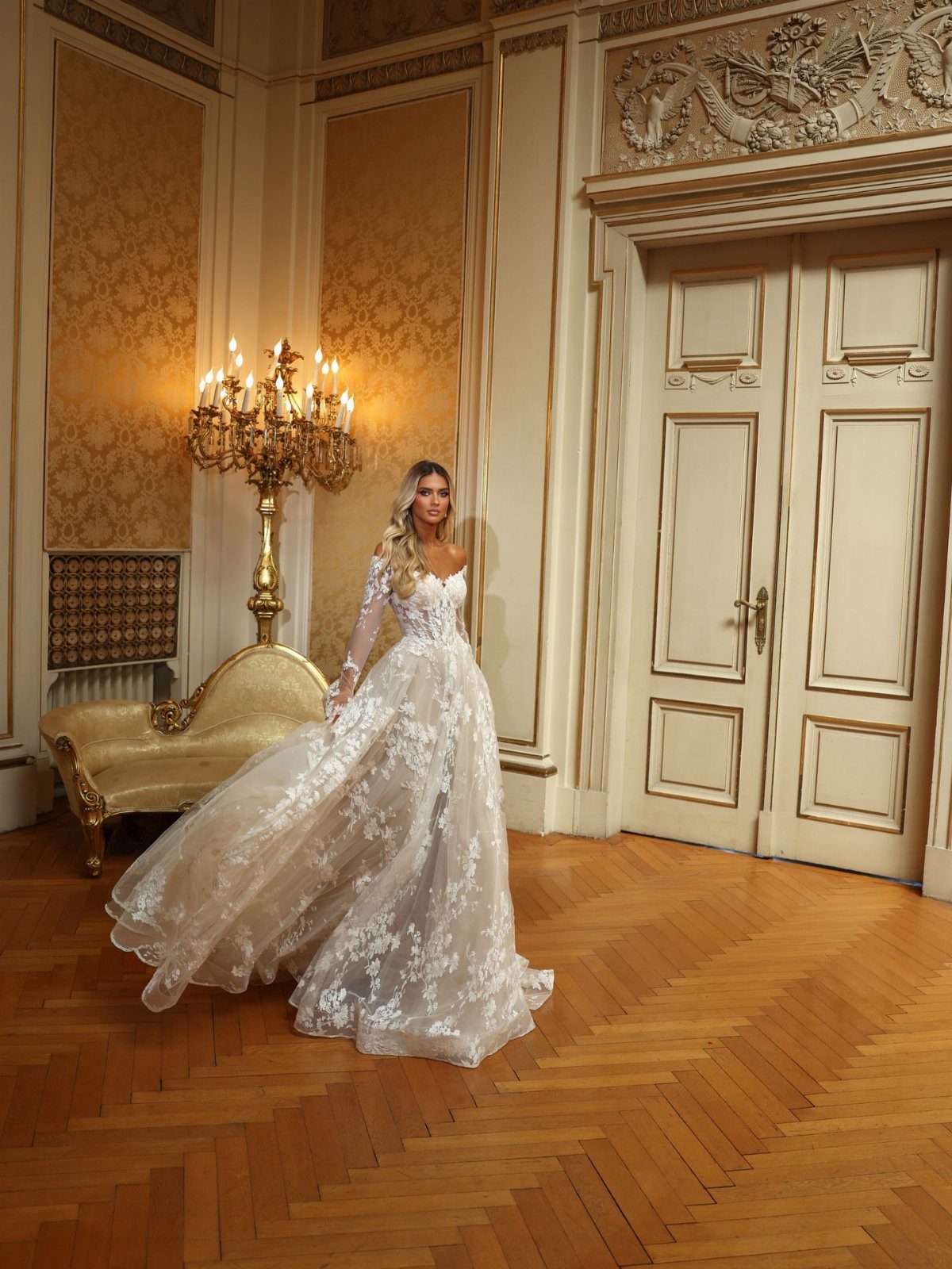 Woman wearing a white wedding gown with detailed floral lace patterns on the voluminous skirt.