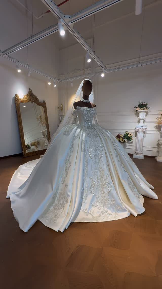 A voluminous white satin ballgown with silver embroidery displayed on a mannequin.