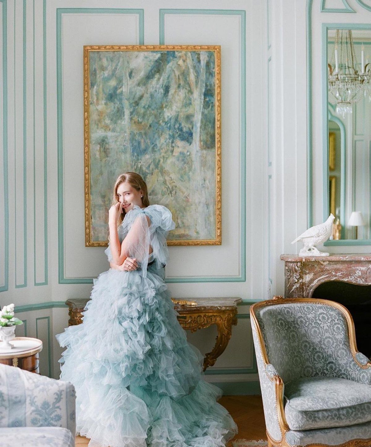 Woman wearing a voluminous light blue ruffled tulle wedding dress in an elegant room.