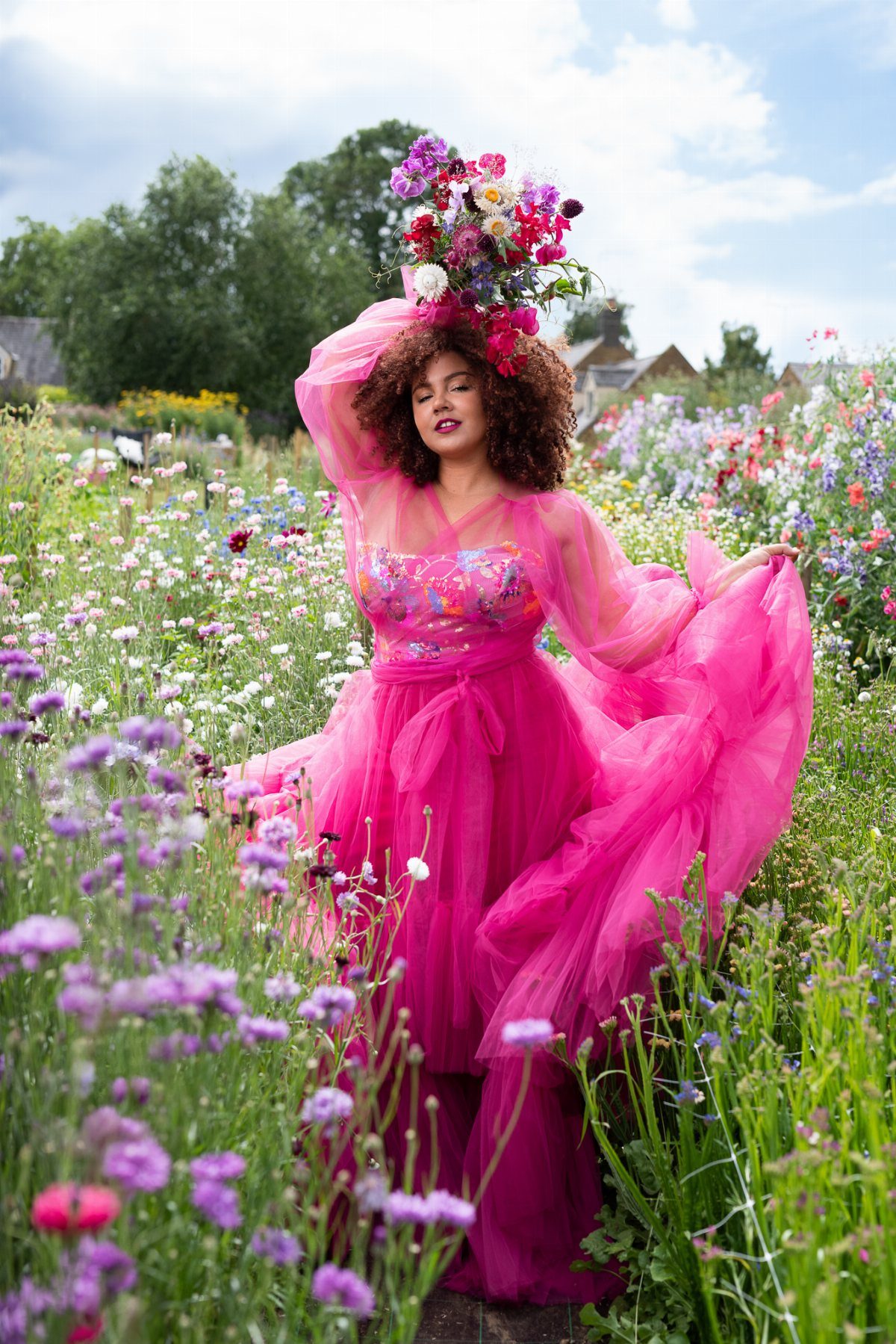 Woman in a bright hot pink tulle wedding dress standing in a wildflower garden.
