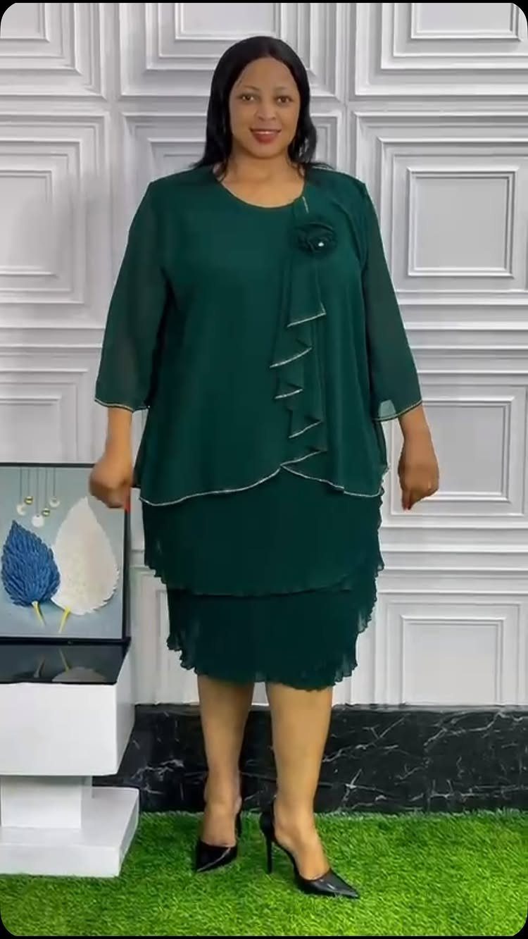 A woman wearing an elegant dark green chiffon church suit and black heels.