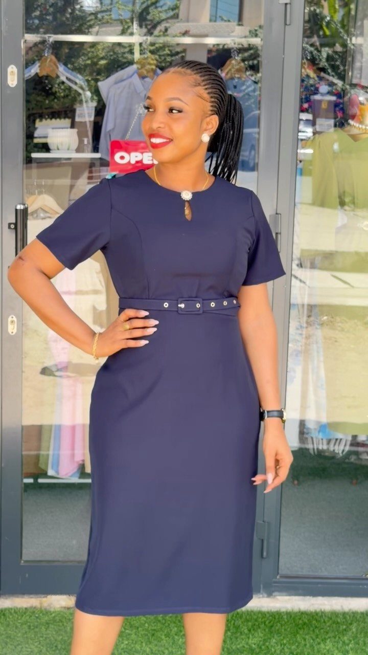 Woman posing in a navy blue short-sleeved midi dress with a belted waist.