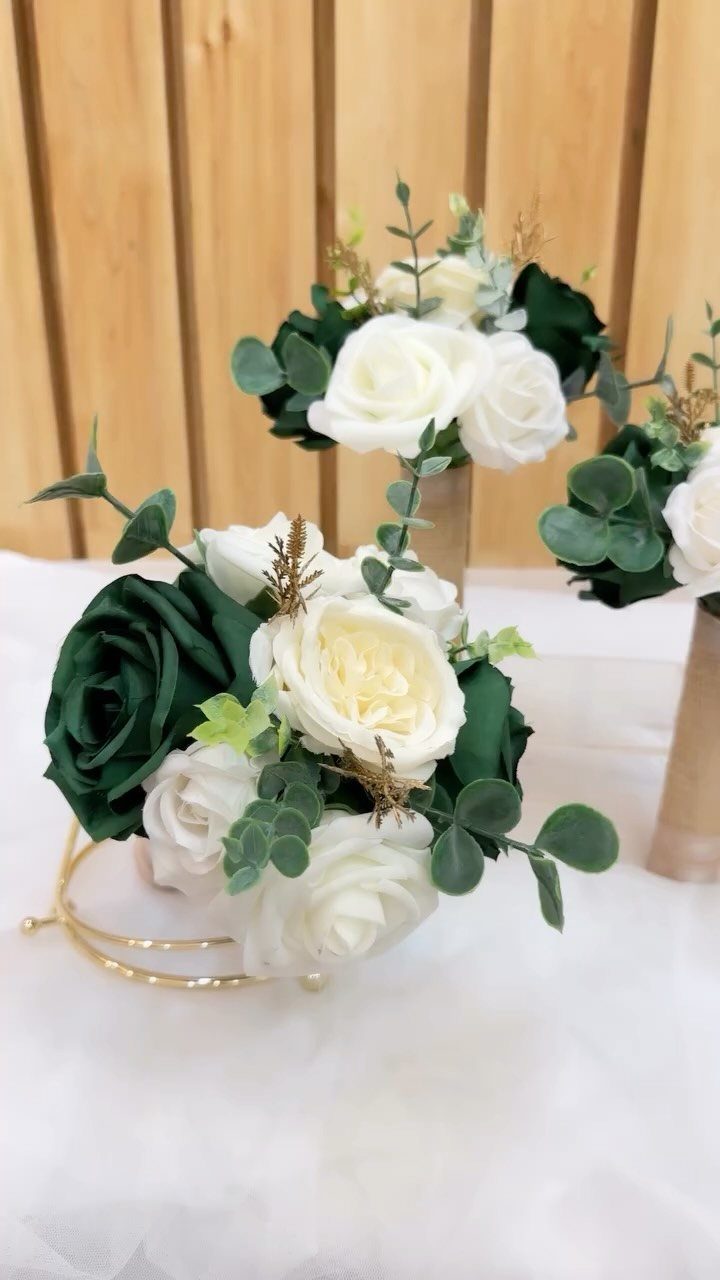 White and emerald green rose floral arrangements with eucalyptus leaves in gold holders.