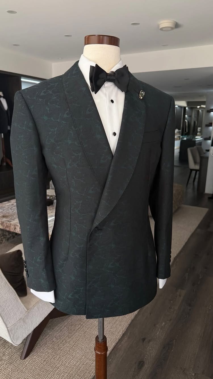 Dark emerald green patterned tuxedo jacket on a mannequin with a black bow tie.