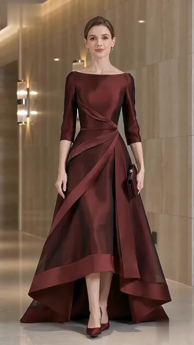 Woman in a burgundy satin high-low formal dress posing in a hallway.
