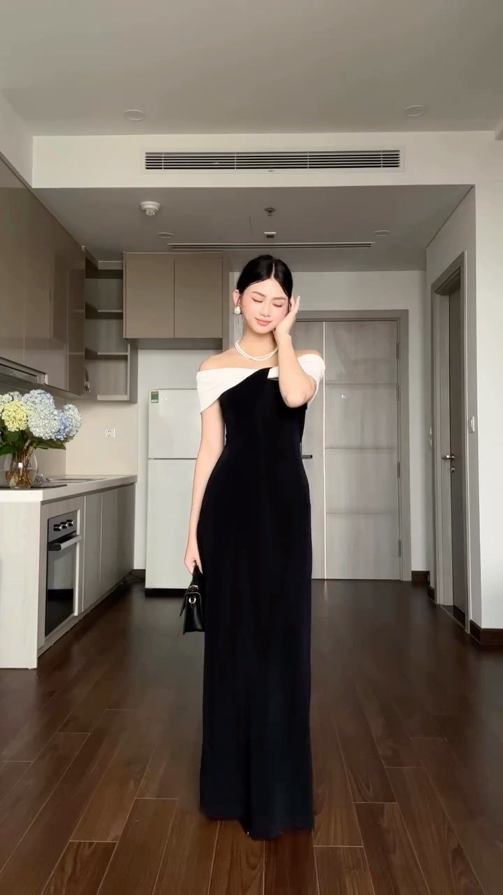 Woman in a black and white formal gown wearing a simple pearl necklace.