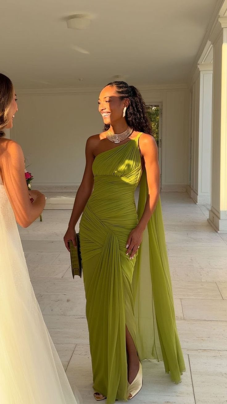Woman in a lime green one-shoulder formal gown with a cape at a wedding.