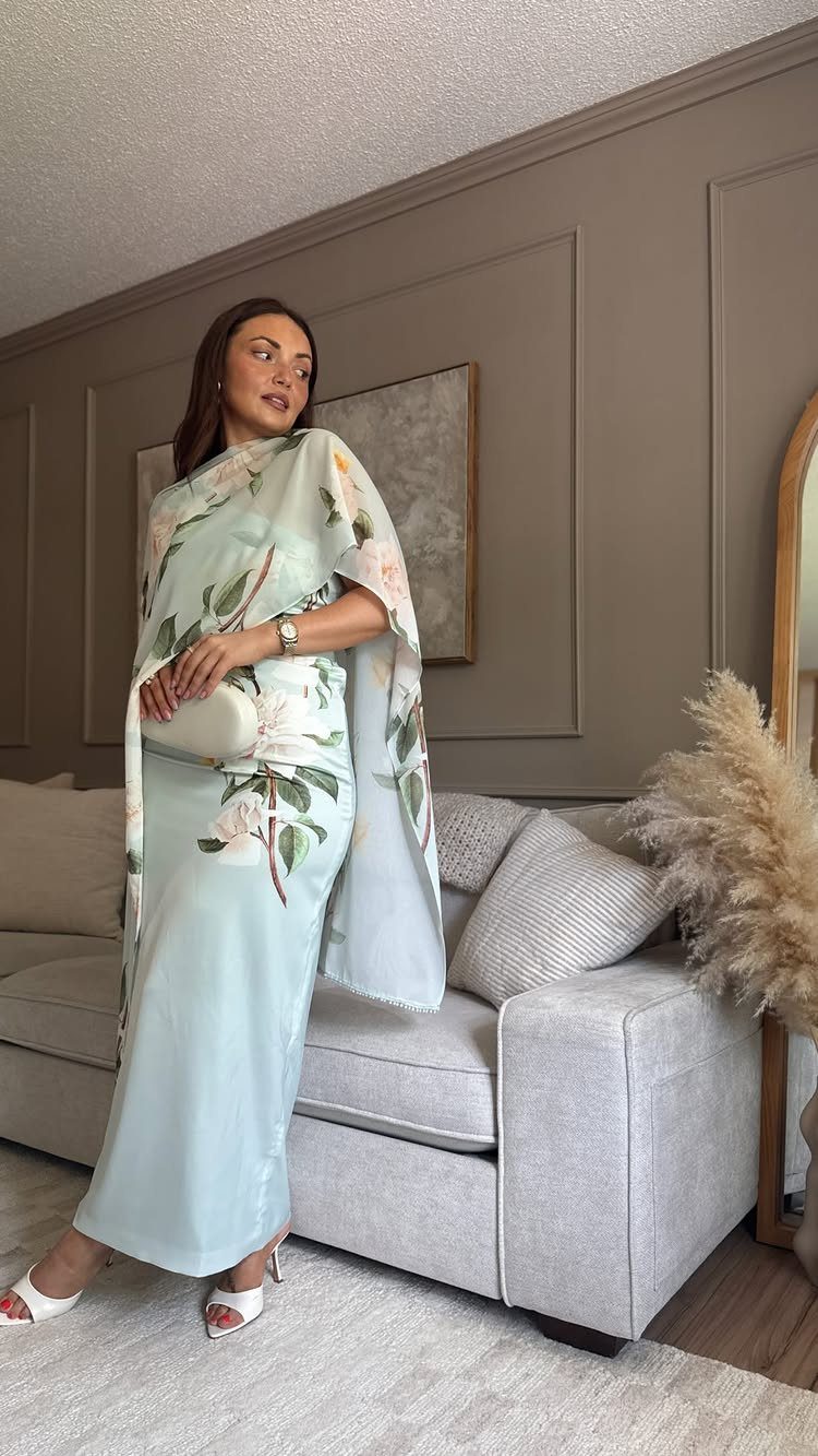 A woman in a light blue floral maxi dress posing in a living room.