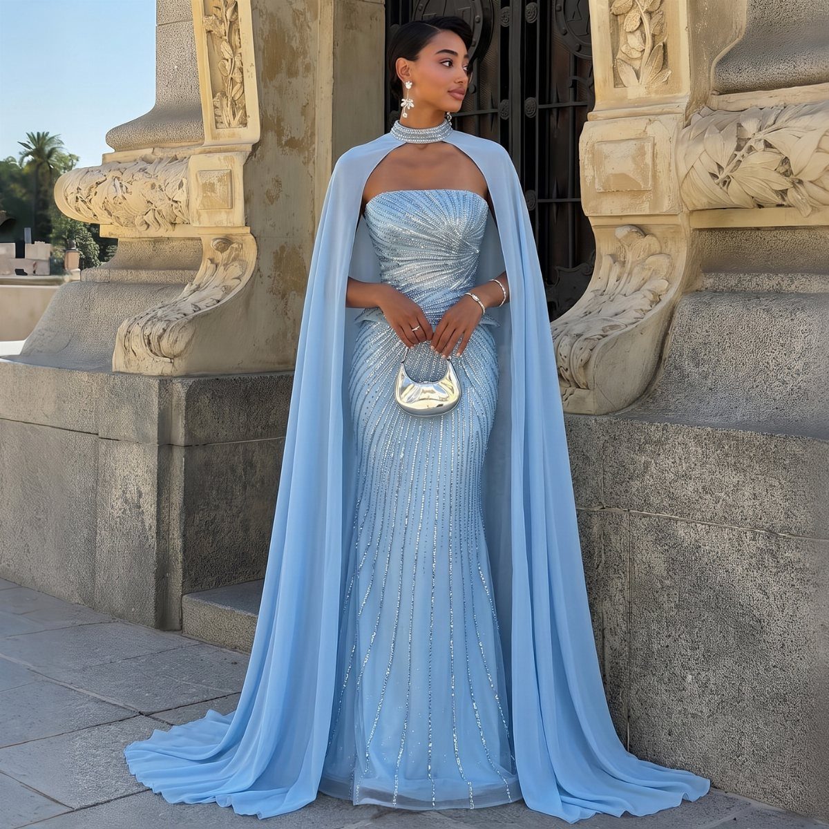 A woman in a light blue sequined mermaid gown with a long flowing cape.