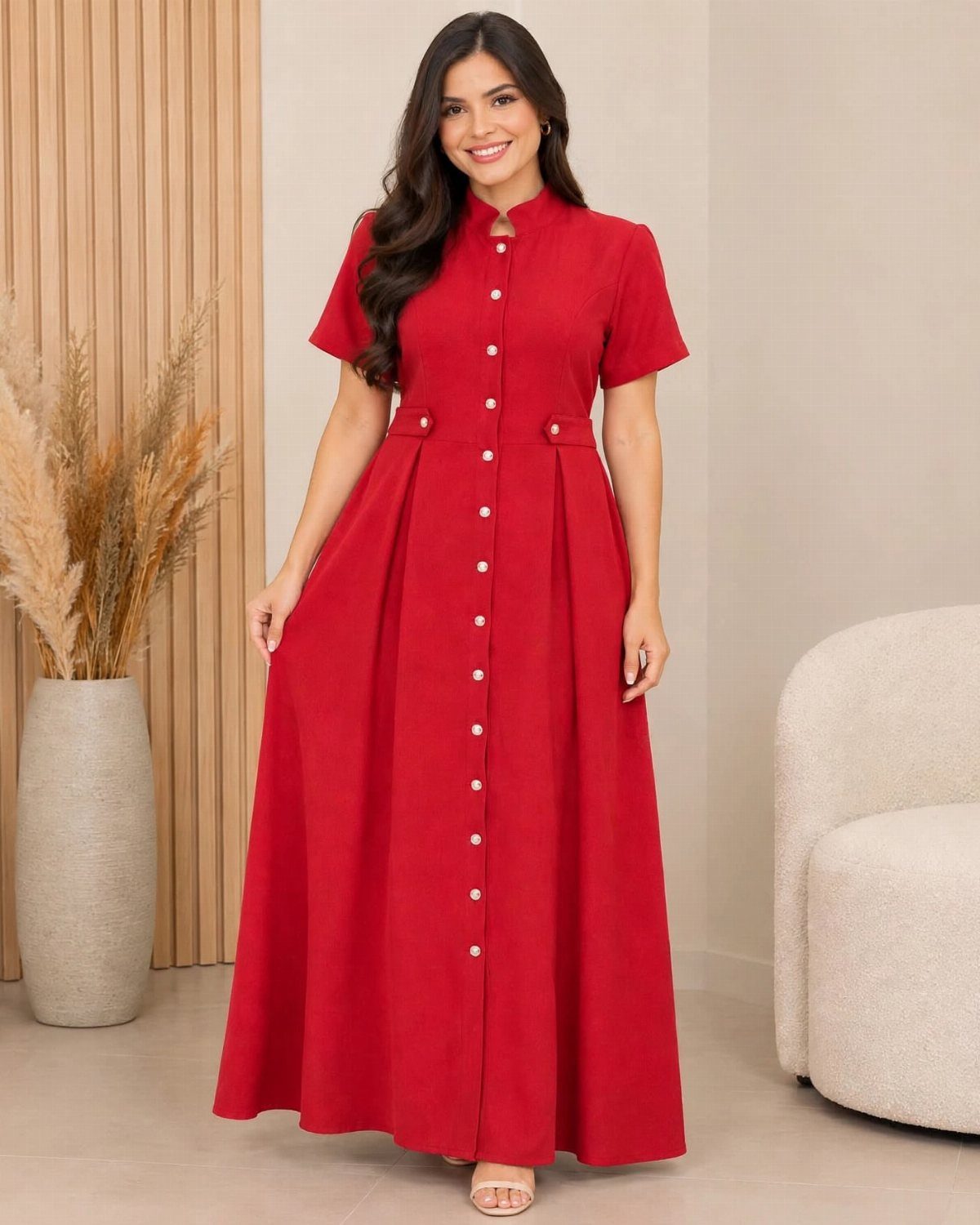 A woman in a long red button-down maxi dress with short sleeves standing in a room.