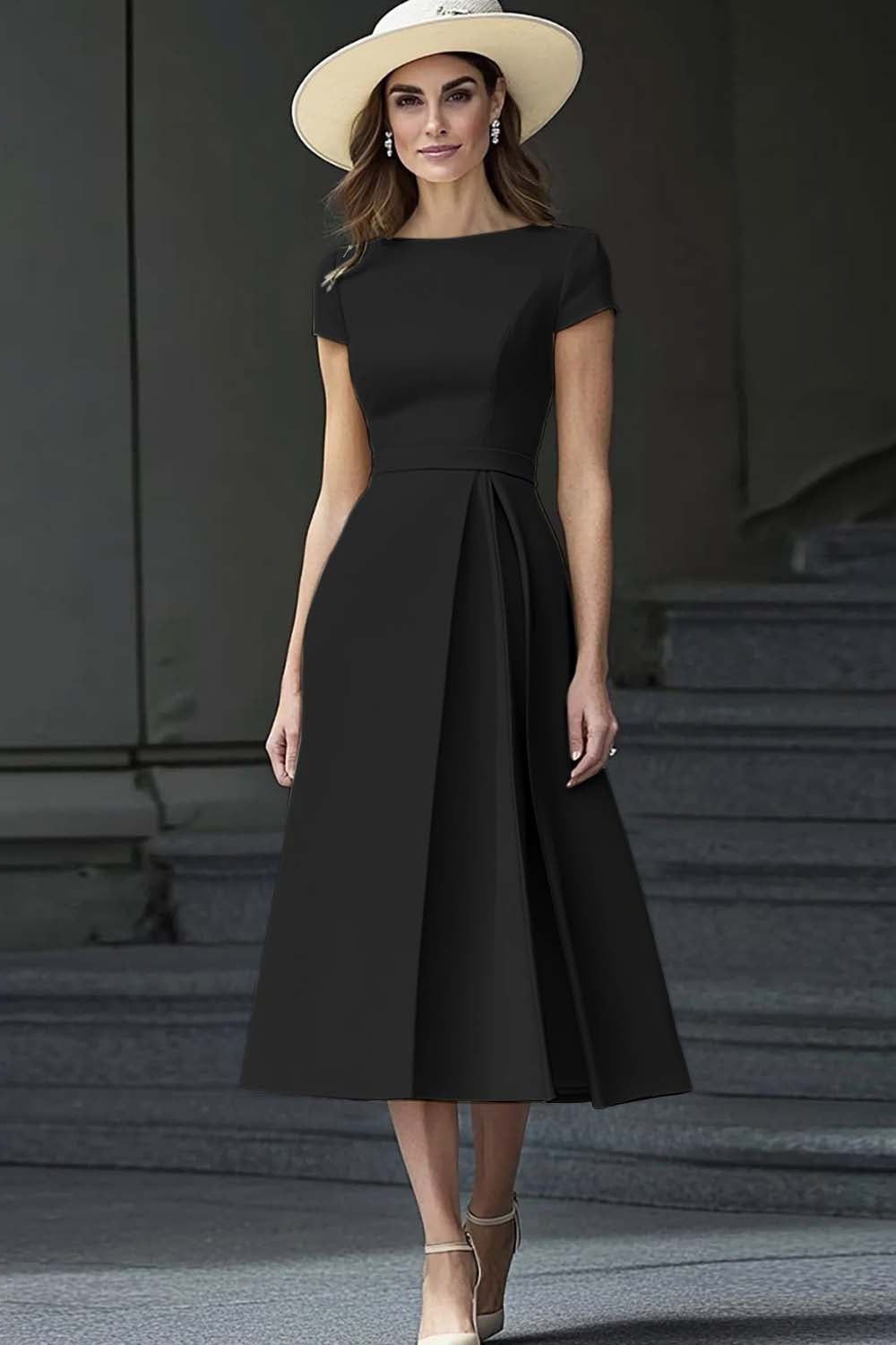 Woman in a black short-sleeved midi dress and straw hat standing on stone stairs.