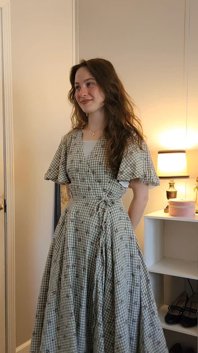 A young woman smiling while wearing a green and white gingham modest summer dress.
