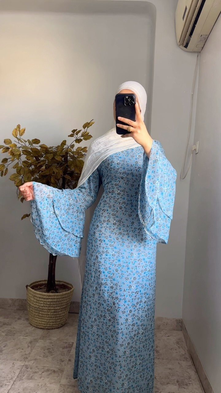 Person in a blue floral maxi dress with bell sleeves and a white hijab.