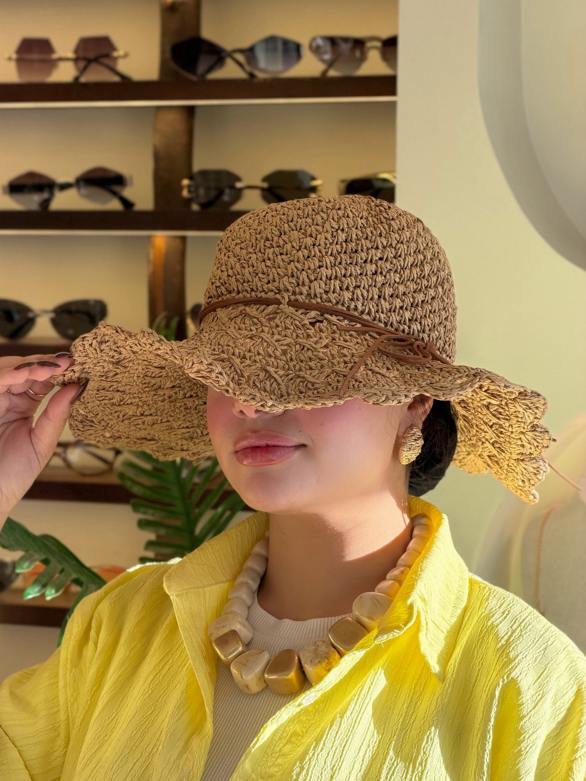 A person wearing a large, ruffled straw hat and a bright yellow shirt.