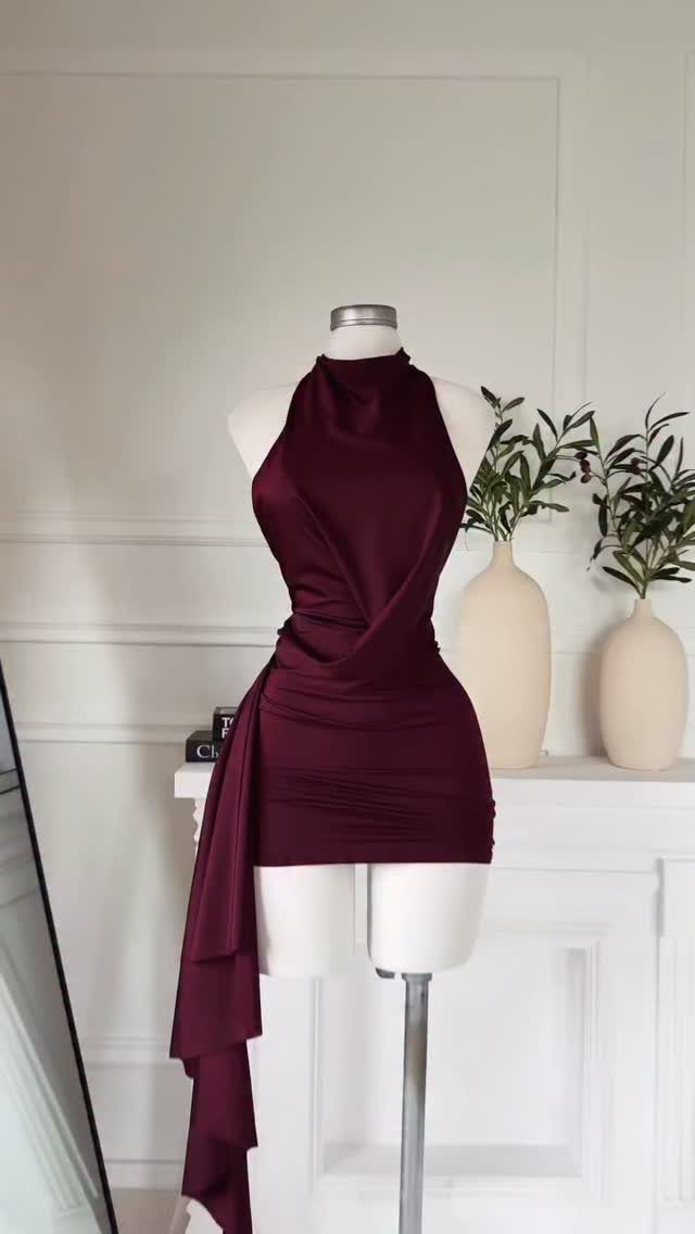 Plum satin mini dress with a halter neck and draped fabric on a white mannequin.