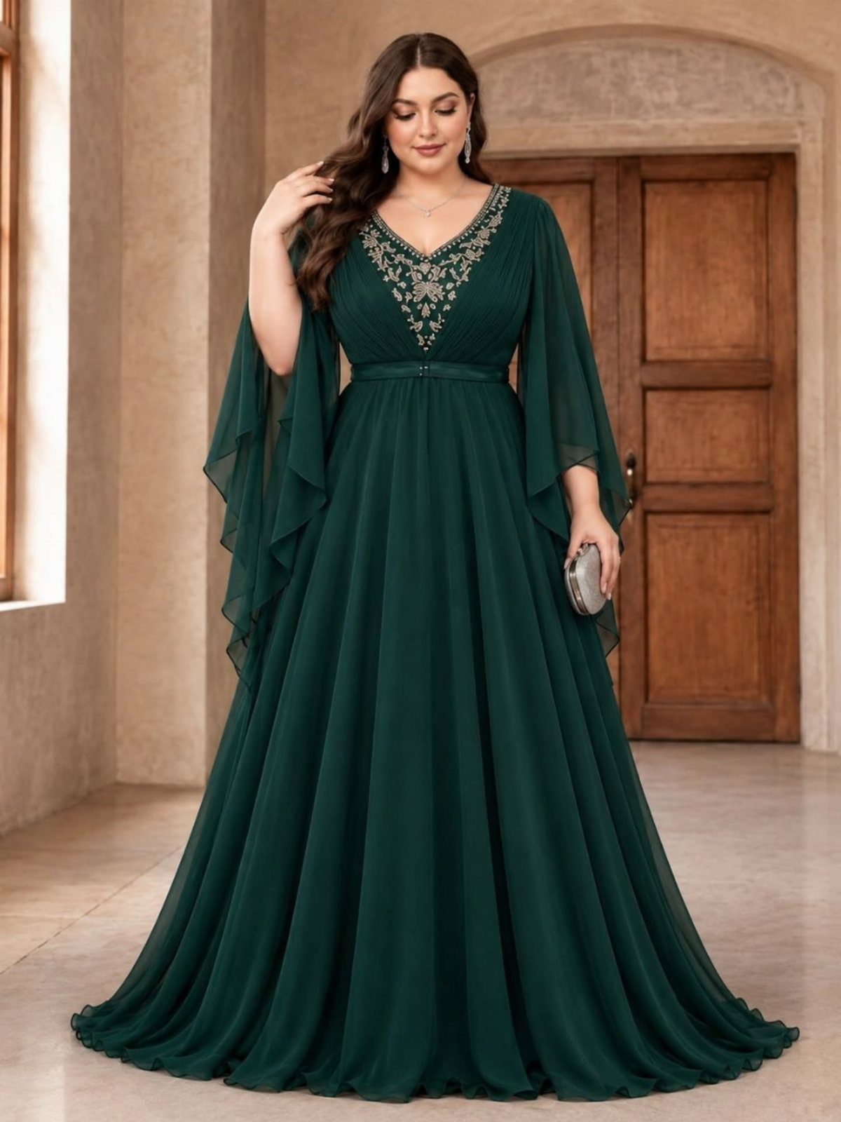 Plus size woman wearing an emerald green chiffon maxi dress with silver beaded embroidery and flowing sleeves.