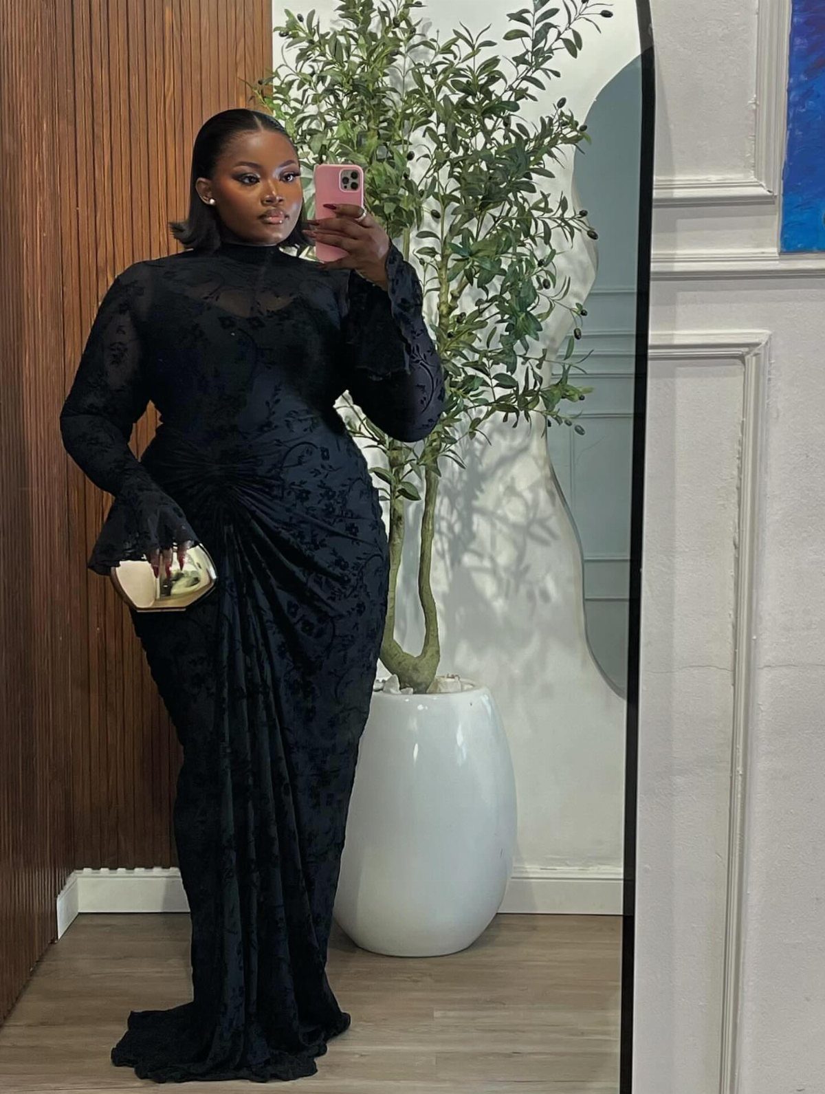 Woman in a long-sleeved black lace maxi dress posing for a mirror selfie.