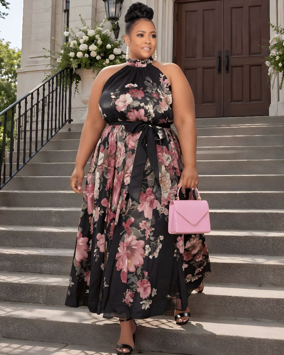 A woman in a black floral halter neck maxi dress walking down stone stairs.