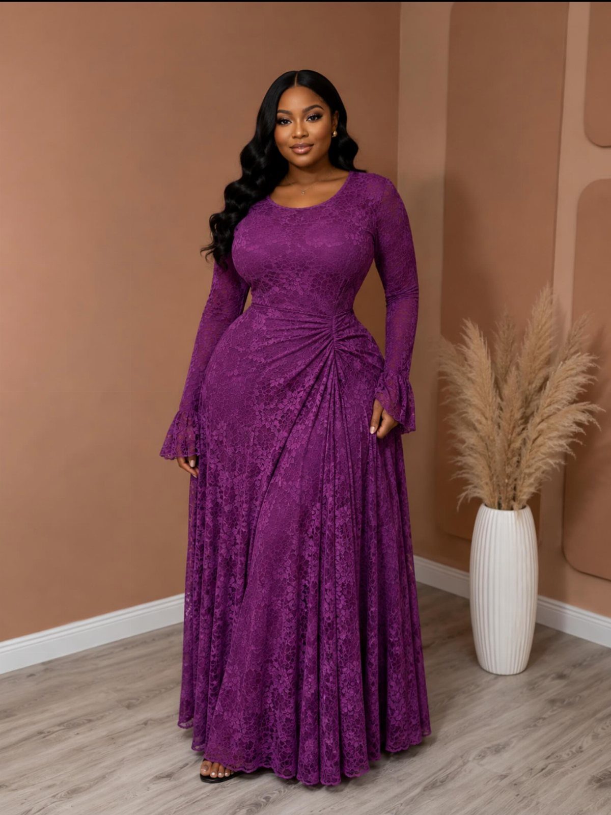 A woman wearing a long-sleeved purple lace maxi dress standing in a neutral-toned room.