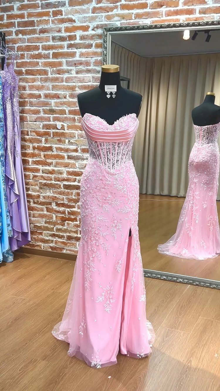 Pink strapless lace prom dress with a fitted bodice and flared skirt on a mannequin.