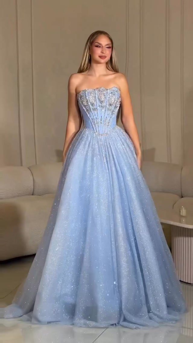 Woman wearing a sparkling light blue strapless ball gown with a fitted bodice.