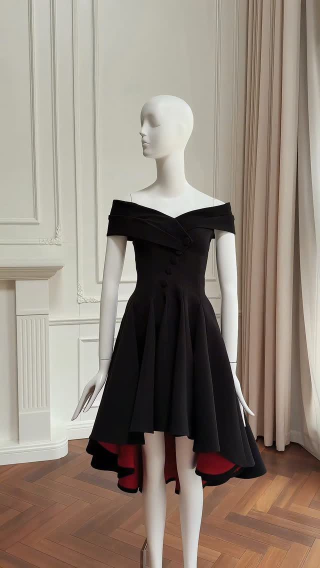 Black off-the-shoulder high-low dress with red lining on a white mannequin.