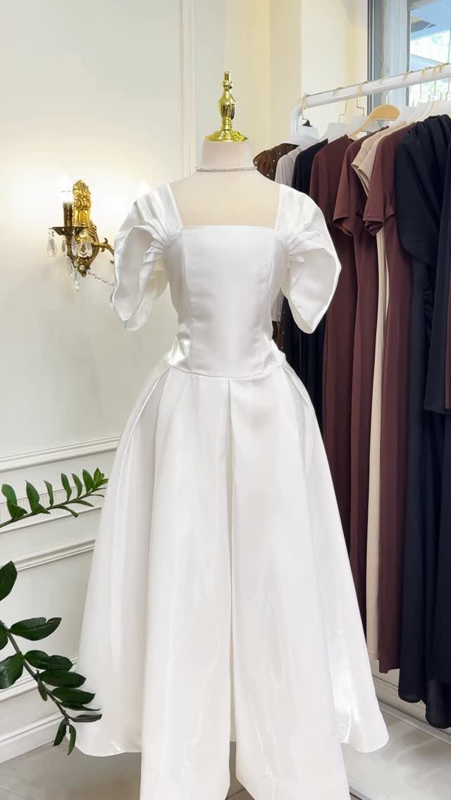 White satin ball gown with puffed sleeves and a full skirt displayed on a mannequin.