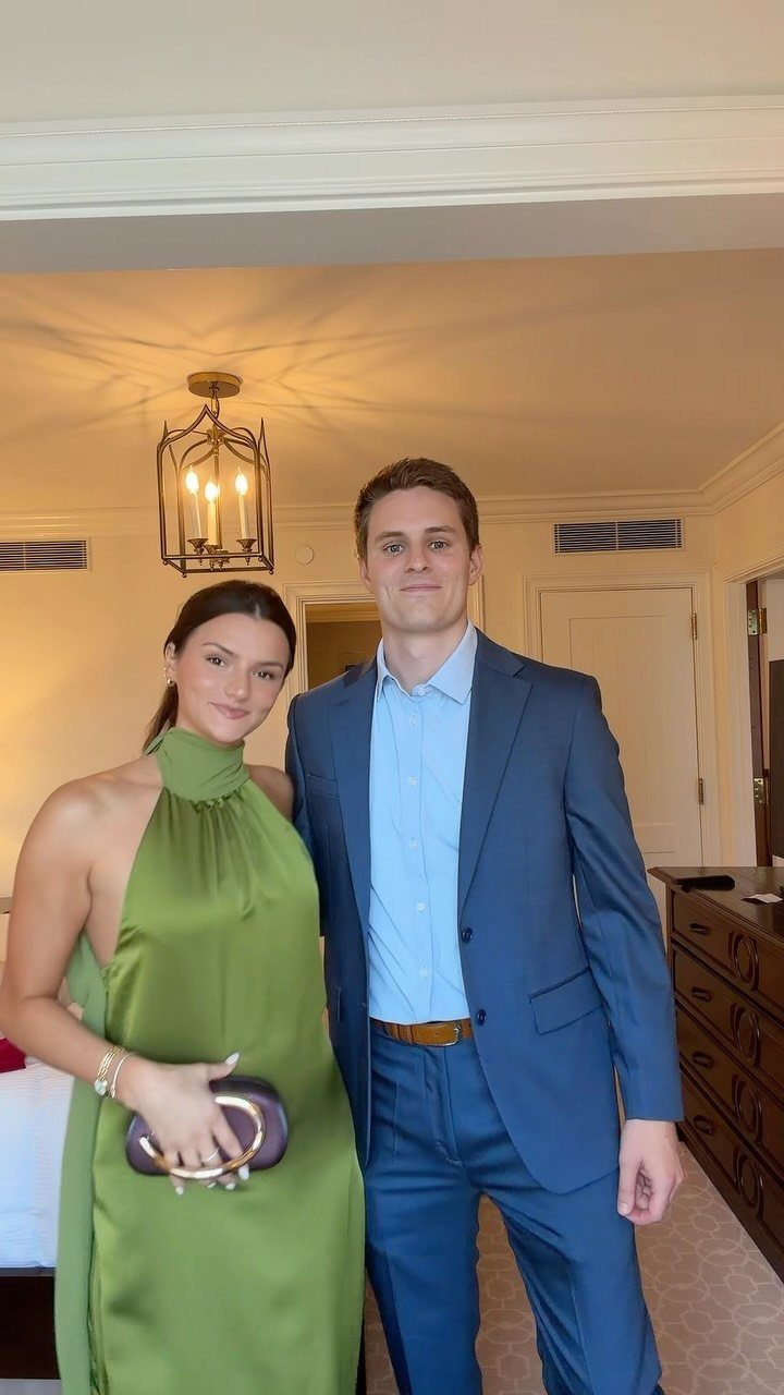 A woman in a green satin dress and a man in a blue suit posing together.