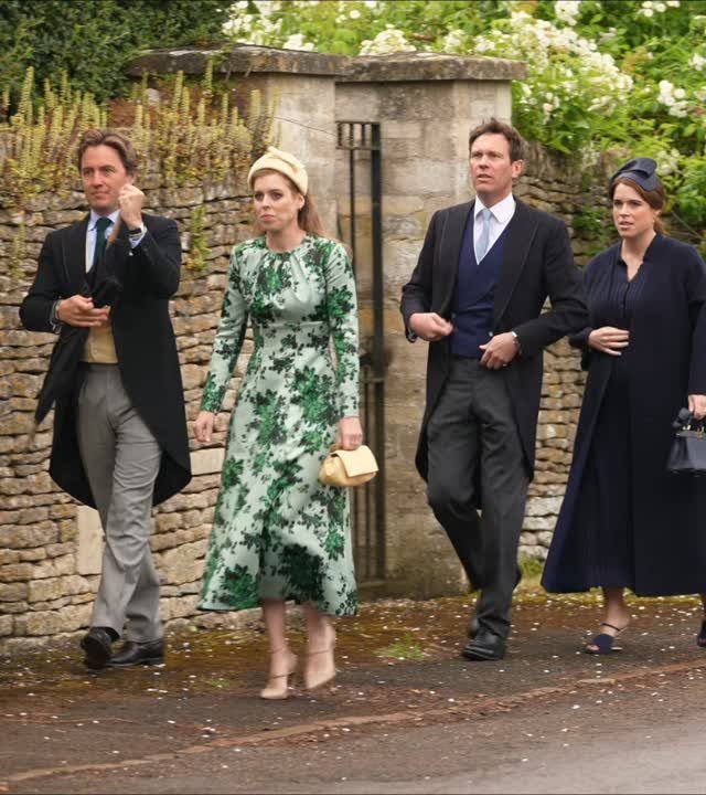 A woman in a green floral dress and cream hat walking with others outdoors.