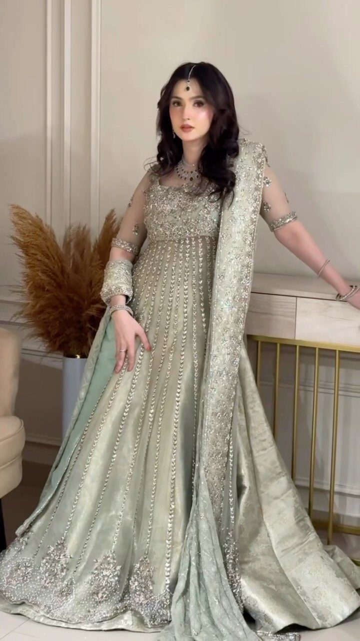 Woman in an embroidered sage green lehenga wearing ornate silver bridal jewelry.