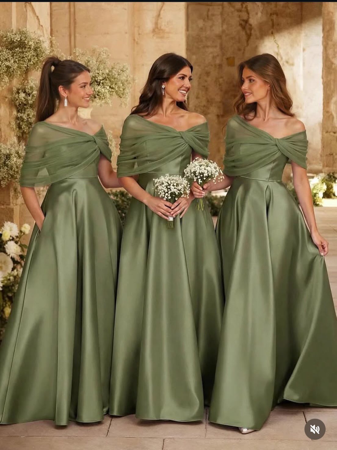 Three women in sage green satin bridesmaid dresses holding small white flower bouquets.