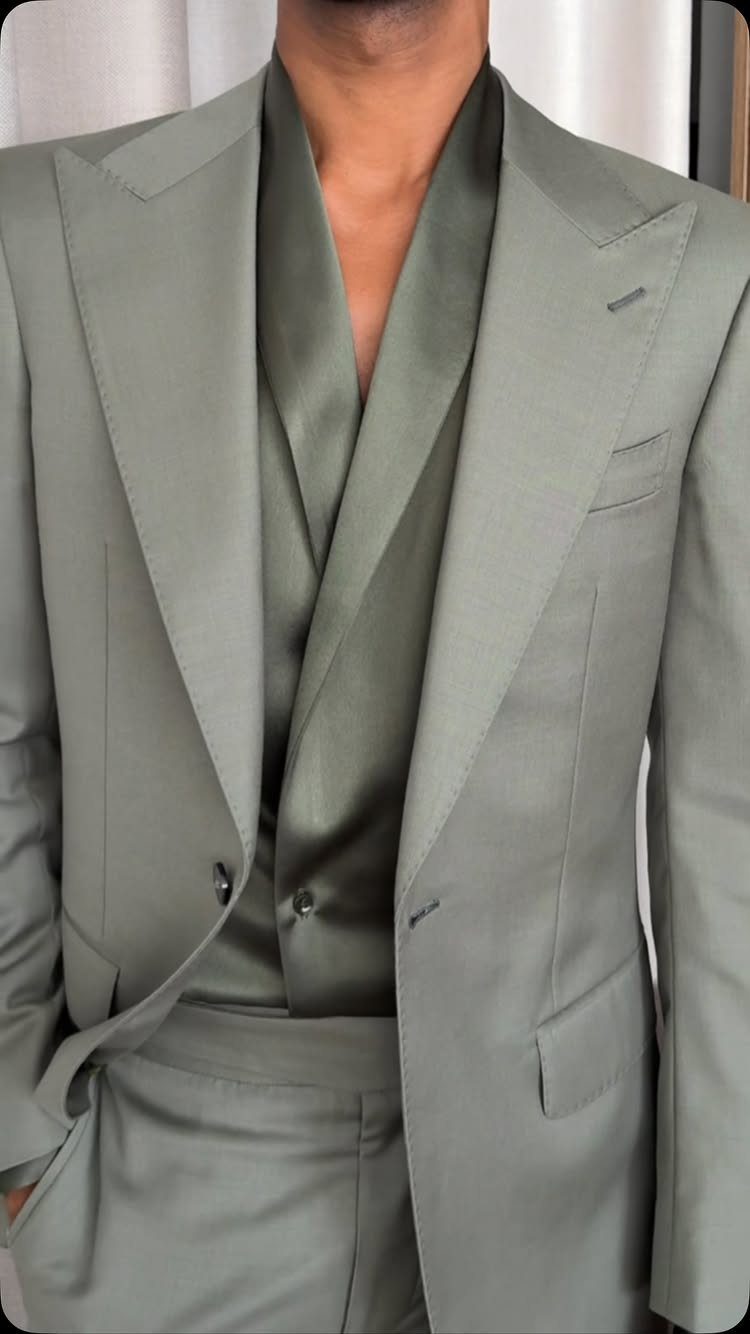 A man wearing a tailored sage green three-piece wedding suit with a waistcoat.