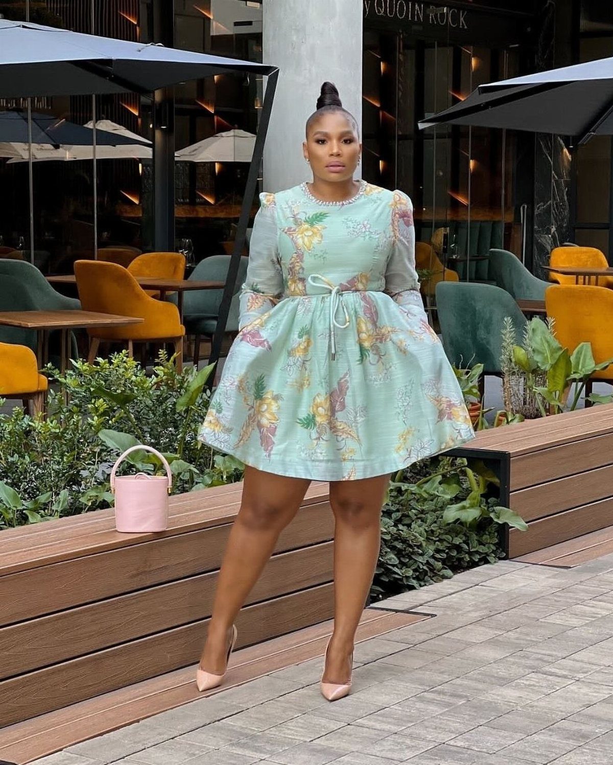 Woman posing in a short mint green floral print dress with long sleeves and a flared skirt.