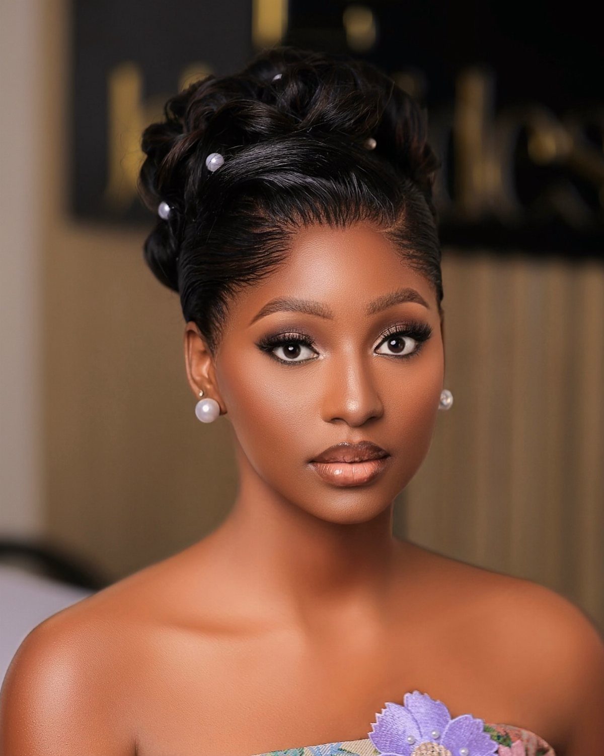 Woman with dark hair styled in a voluminous sleek updo decorated with small white pearls.