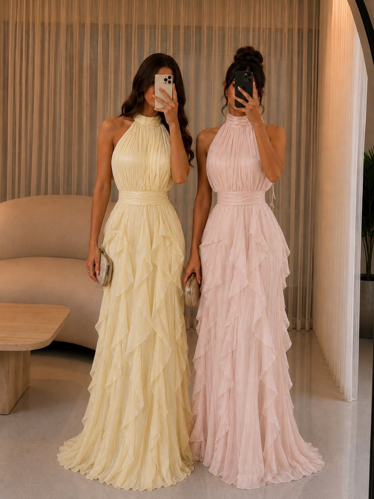 Two women posing in long, ruffled halter-neck maxi dresses in pale yellow and light pink.