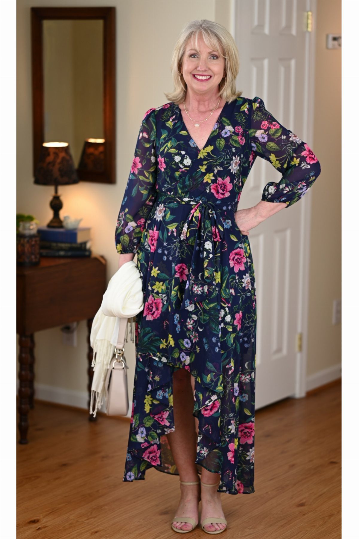 Woman wearing a navy blue floral wrap dress and beige block heels indoors.
