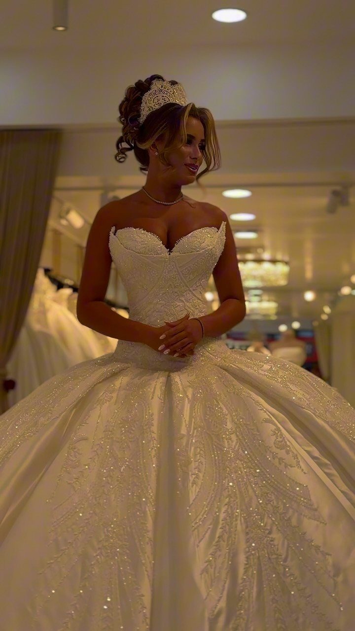 Woman in a voluminous white lace ball gown wedding dress wearing a tiara.