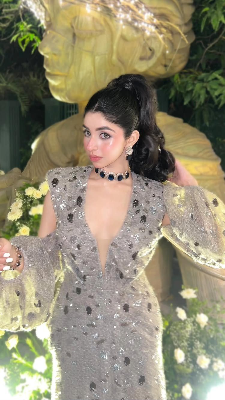Woman in a shimmering sequined grey gown with voluminous sleeves posing outdoors.