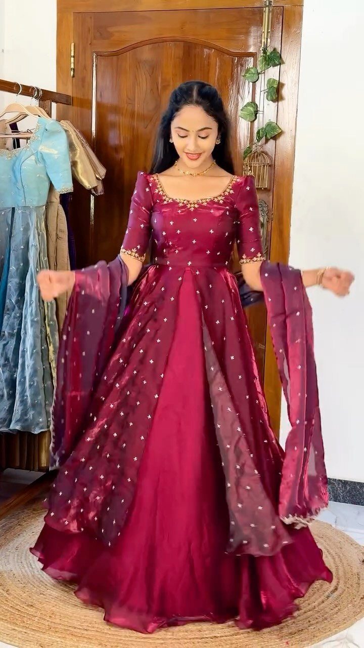 A woman wearing a maroon embellished gown with a matching sheer dupatta while posing indoors.